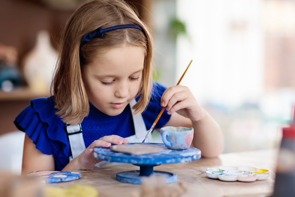 Child at pottery wheel. Kids arts and crafts class